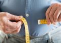 Overweight man measuring stomach